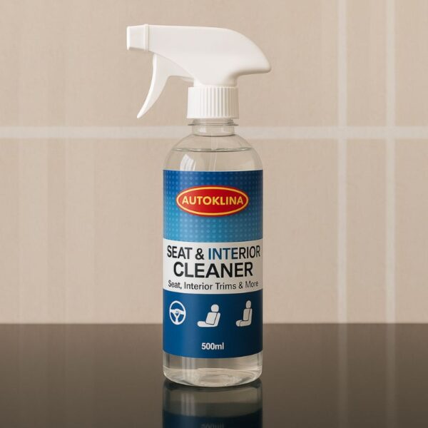 Une bouteille en plastique transparent avec un vaporisateur blanc, contenant le produit Autoklina Seat & Interior Cleaner (Nettoyant pour sièges et intérieur) de 500 ml. Le flacon est posé sur une surface réfléchissante sombre devant un mur de carreaux clairs.